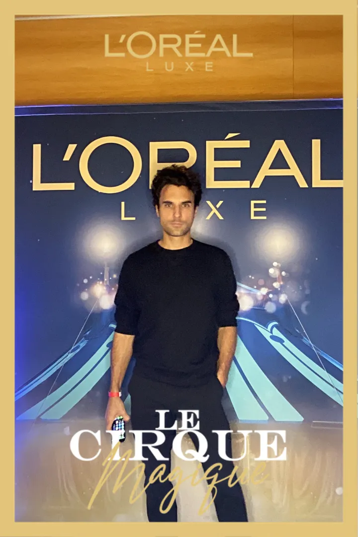 Un homme posant devant le backdrop L'Oréal Luxe au Cirque Magique avec Catchingbox Photobooth