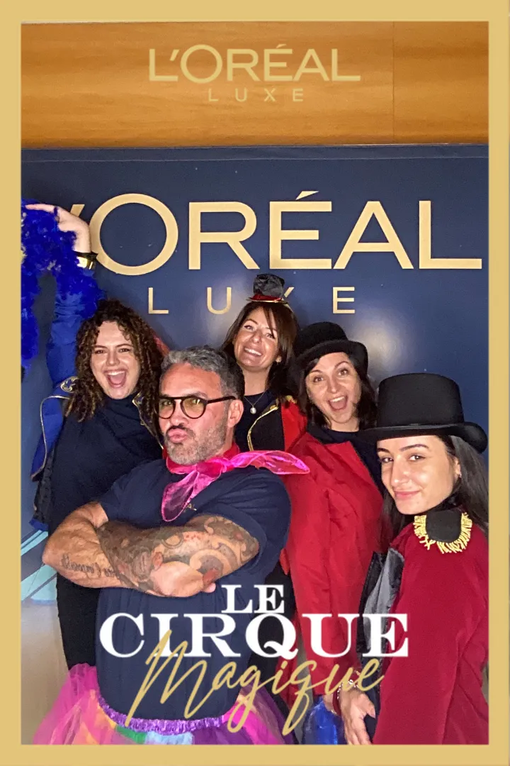 Groupe de personnes posant devant le backdrop L'Oréal Luxe au Cirque Magique avec Catchingbox Photobooth